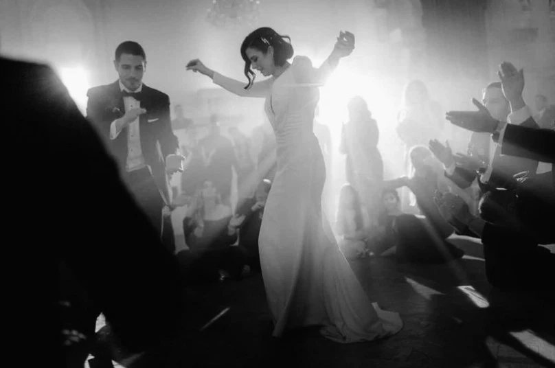 The bride mid-spin during the first dance, backlit through haze as guests watch