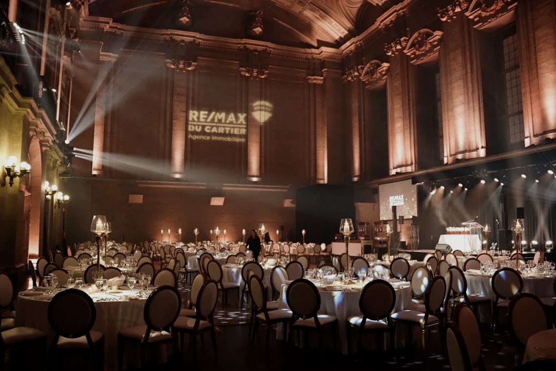 Candlelit gala tables in a grand hall with the client's logo projected above the stage at Théâtre St-James, Montréal