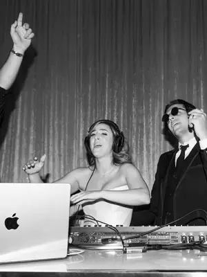 The bride behind the decks in headphones, taking over the booth with her guests
