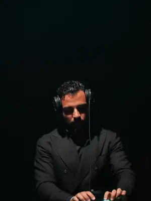 DJ MAJD in a dark suit reading the room from behind the booth